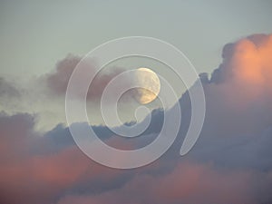 Background with rising moon above pink sunset clouds