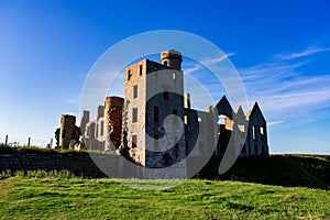 Slains Castle East wall in sunny day and blue sky zoom out