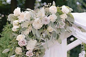 Beautiful wedding arch, decorated with biege cloth and flowers, closeup