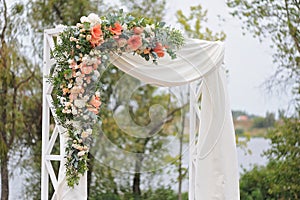 Beautiful wedding arch, decorated with white cloth and flowers, closeup