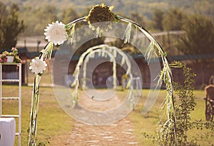 Beautiful wedding arch of paper flowers in a field or meadow. Preparation for a wedding event