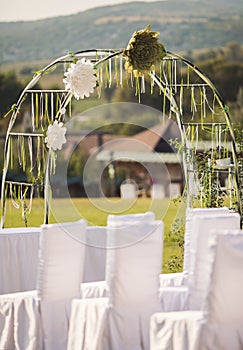 Beautiful wedding arch of paper flowers in a field or meadow. Preparation for a wedding event