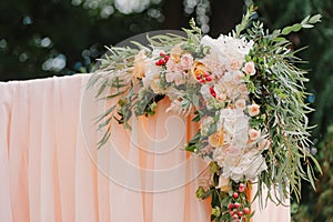 Beautiful wedding archway. Arch decorated with peachy cloth and flowers