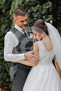 A beautiful wedding, a beautiful couple in love, laughing and kissing against the background of a green garden