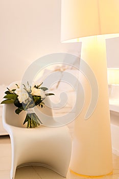 Beautiful wedding bouquet on a chair. Beige lamp