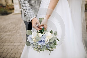 Beautiful wedding bouquet in the hands of the bride and groom