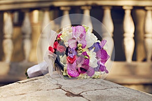 A beautiful wedding bouquet lying on a stone over old house