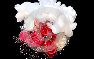 Beautiful wedding bouquet of red and white roses and white watercolor ink in water on a black background