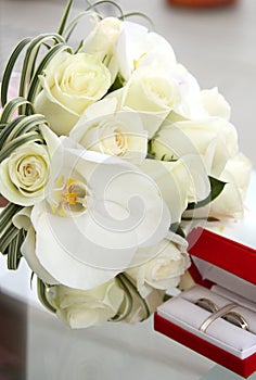 Beautiful wedding bouquet of roses and orchids and red velvet box with gold and platinum wedding rings