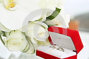 Beautiful wedding bouquet of roses and orchids and red velvet box with gold and platinum wedding rings