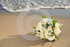 Beautiful wedding bouquet on sandy beach near sea