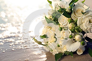 Beautiful wedding bouquet on sandy beach near sea, closeup. Space for text