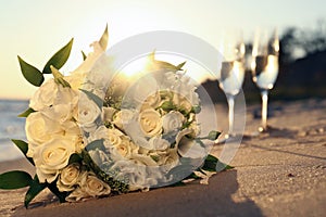 Beautiful wedding bouquet on sandy beach at sunset