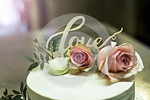 Beautiful wedding cake with cream With text Love on top pink flowers roses