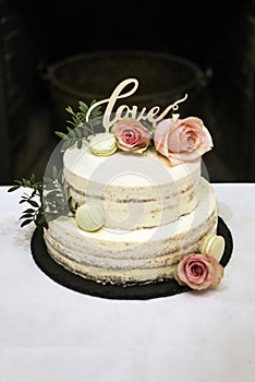 Beautiful wedding cake with cream With text Love on top pink flowers roses