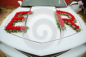 Decorated with flowers as for a wedding . Fresh flowers on the car. Beautiful wedding bouquet on white wedding car . Beautiful