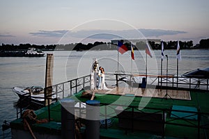 beautiful wedding ceremony by water on dock. bride and groom.