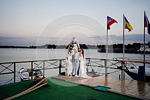 beautiful wedding ceremony by water on dock. bride and groom.