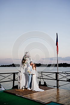 beautiful wedding ceremony by water on dock. bride and groom.