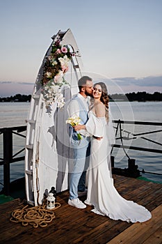 beautiful wedding ceremony by water on dock. bride and groom.