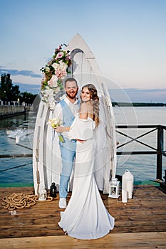 beautiful wedding ceremony by water on dock. bride and groom.