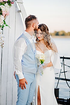 beautiful wedding ceremony by water on dock. bride and groom.