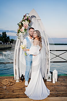 beautiful wedding ceremony by water on dock. bride and groom.