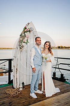 beautiful wedding ceremony by water on dock. bride and groom.