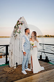 beautiful wedding ceremony by water on dock. bride and groom.