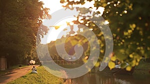 Beautiful wedding couple with balloons sitting on the grass at the picturesque golden autumn park on sunset. Moment of