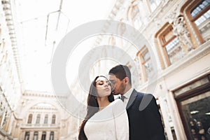 Beautiful wedding couple, bride, groom kissing and hugging against the background of old building