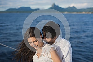 Beautiful wedding couple bride and groom on yacht at wedding day outdoors in the sea. Happy marriage couple kissing on