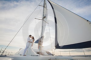 Beautiful wedding couple bride and groom on yacht at wedding day outdoors in the sea. Happy marriage couple kissing on