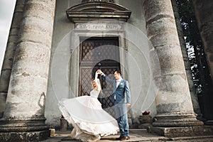 Beautiful wedding couple just married and dancing near old building