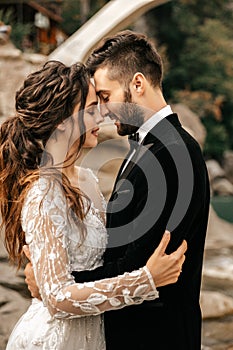 Beautiful wedding couple laugh and kiss on the background of stones