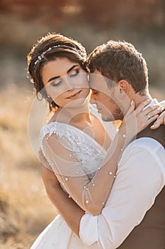 Beautiful wedding couple laughing and kissing against the background of stones.