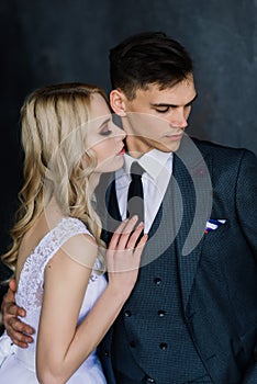 Beautiful wedding couple. Luxurious dress of the bride and stylish suit of the groom, studio photo shoot