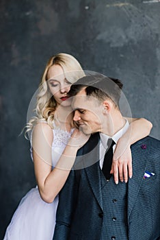 Beautiful wedding couple. Luxurious dress of the bride and stylish suit of the groom, studio photo shoot