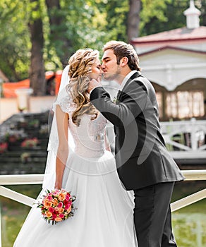 Beautiful wedding couple in park. They kiss and hug each other