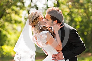 Beautiful wedding couple in park. They kiss and hug each other