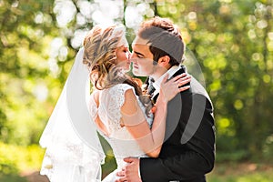 Beautiful wedding couple in park. They kiss and hug each other