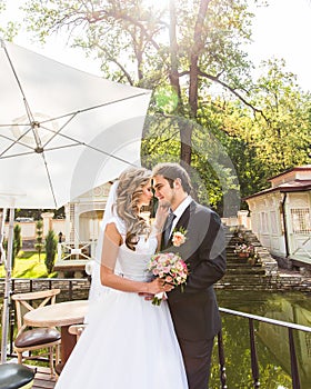 Beautiful wedding couple in park. They kiss and hug each other