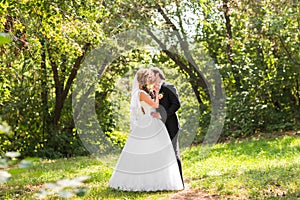 Beautiful wedding couple in park. They kiss and hug each other