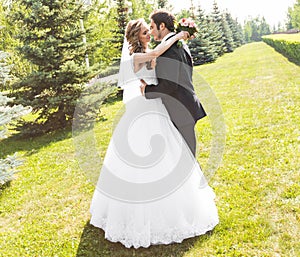 Beautiful wedding couple in park. They kiss and hug each other