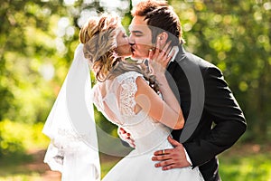 Beautiful wedding couple in park. They kiss and hug each other