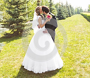 Beautiful wedding couple in park. They kiss and hug each other