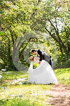 Beautiful wedding couple in park. They kiss and hug each other