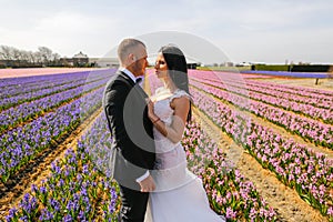 Beautiful wedding couple posing in a field with flowers