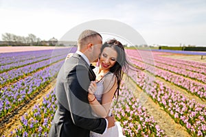 Beautiful wedding couple posing in a field with flowers