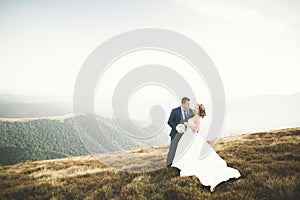 Beautiful wedding couple posing on top of a mountain at sunset